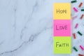 Love, hope, and faith handwritten words on colorful notes with decorative clothespins on white marble background