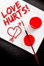 Love hurts text painted on a blank paper