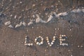 Love inscription made of seashells on the beach.