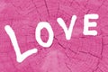 Love. The inscription `Love` on a tinted pink wooden background.