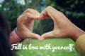 Love inspirational motivational quote - Fall in love with yourself. With hands making love sign against green nature park Royalty Free Stock Photo
