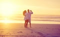 Love and laughter. Full length shot of an affectionate mature couple dancing on the beach at sunset. Royalty Free Stock Photo