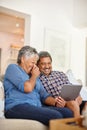 Love and laughter online. a happy senior couple using a digital tablet together at home. Royalty Free Stock Photo