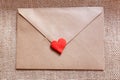 Love letter in a craft envelope with clay red heart on a jute background