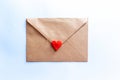 Love letter in a craft envelope with clay red heart on light blue background