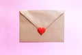 Love letter in a craft envelope with clay red heart on pink background