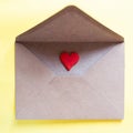 Love letter in a craft envelope with clay red heart on yellow background