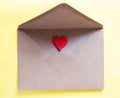 Love letter in a craft envelope with clay red heart on yellow background