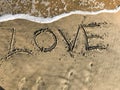 Love letter drawn on beach sand with sea waves Royalty Free Stock Photo