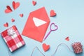 Love letter Valentine day concept. Red paper envelope with a white note inside and paper hearts a gift on a blue background Royalty Free Stock Photo