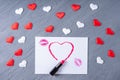 Love letter. White paper, lipstick kisses, heart drawn with lipstick and red and white hearts on gray background
