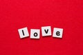 Love lettering word written by black printed letters on white sheets of paper on red background