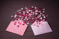 Love letters. Pink and white envelopes with  red, white and pink hearts inside on grey wooden  background Royalty Free Stock Photo