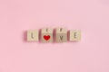 LOVE, LIFE text and red heart on Wooden cubes on pink background Royalty Free Stock Photo