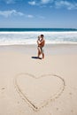 In love with life. a young couple enjoying a romantic moment at the beach next to a drawing of a heart in the sand. Royalty Free Stock Photo