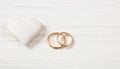 Close up view of golden wedding rings and a white heart, isolated, copy space, on a white wooden background. Royalty Free Stock Photo