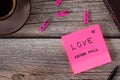 Love never fails, handwritten biblical verse on pink note with cup of coffee and holy bible book on wooden background Royalty Free Stock Photo