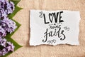 Love never fails - pink flowers and calligraphy text on paper, bible quote