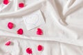 Love note with hand drawn heart on white bed sheets with pink rose petals