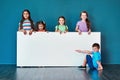 We love it And other kids will too. Studio portrait of a diverse group of kids standing behind a large blank banner Royalty Free Stock Photo