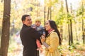 Love, parenthood, family, season and people concept - smiling couple with baby in autumn park