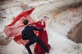 Love and passion, concept. Beautiful young couple dancing in desert. The man in black and woman in red Royalty Free Stock Photo