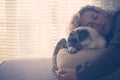 Love for people and dogs with beautiful caucasan adult woman sleeping with best friend pug on the sofa at home - window light for Royalty Free Stock Photo