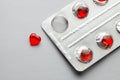 Love pills. Blister pack with red heart shaped pills. Tablets for lovers or potency. Gray background Royalty Free Stock Photo