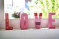 love in pink letters in front of the window