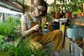 Young female care of potted plants after work, relax in indoor garden. Florist woman entrepreneur Royalty Free Stock Photo