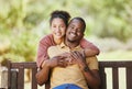 Love, portrait and couple hug in a garden, happy and smile while sitting, relax and bond in nature. Face, black family Royalty Free Stock Photo