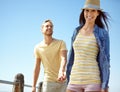 Love, relax and couple at the beach, holding hands and laughing while bonding against blue sky background. Happy, travel Royalty Free Stock Photo