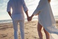 Love, romance on the beach. Young beautiful couple, woman, man, in white loose flying clothes, walk, along the seashore. Royalty Free Stock Photo