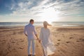 Love, romance on the beach. Young beautiful couple, woman, man, in white loose flying clothes, walk, along the seashore. Royalty Free Stock Photo