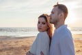 Love, romance, walk. Airy portrait of beautiful couple kissing on background of sunset sea, sandy beach and clouds. Royalty Free Stock Photo