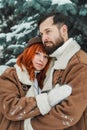 Love romantic couple lovestory. Brutal bearded man, bright red-haired girl woman in winter park. Romantic date, kissing Royalty Free Stock Photo