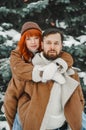 Love romantic couple lovestory. Brutal bearded man, bright red-haired girl woman in winter park. Romantic date, kissing Royalty Free Stock Photo