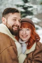 Love romantic couple lovestory. Brutal bearded man, bright red-haired girl woman in winter park. Romantic date, kissing Royalty Free Stock Photo