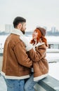 Love romantic couple lovestory. Brutal bearded man, bright red-haired girl woman in winter park. Romantic date, kissing Royalty Free Stock Photo