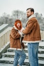 Love romantic couple lovestory. Brutal bearded man, bright red-haired girl woman in winter park. Romantic date, kissing Royalty Free Stock Photo