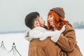 Love romantic couple lovestory. Brutal bearded man, bright red-haired girl woman in winter park. Romantic date, kissing Royalty Free Stock Photo