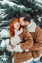 Love romantic couple lovestory. Brutal bearded man, bright red-haired girl woman in winter park. Romantic date, kissing