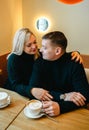 Love romantic couple lovestory. Man hugging woman, kissing blonde girl in cozy coffee shop cafe. Romantic family date Royalty Free Stock Photo