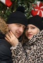 Love romantic couple lovestory. Man hugging woman, kissing girl in Christmas winter fur trees decoration. Romantic date