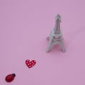 Love runs towards the Eiffel Tower on a pink background. Minimalistic scene