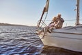 In love with Sailing. A happy senior couple sitting on the side of a sail boat on a calm blue sea. Man hugging his woman Royalty Free Stock Photo