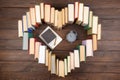 Love science concept. Heart shape of books, graduate cap and clock on wooden desk. Time to take a degree in natural Sciences