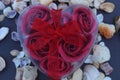 Love shaped red gift box with red decorative artificial rose petals inside.