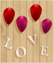 Love sign hanging on balloons on wooden background