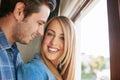 Love starts at home. an affectionate young couple standing at a window in their home.